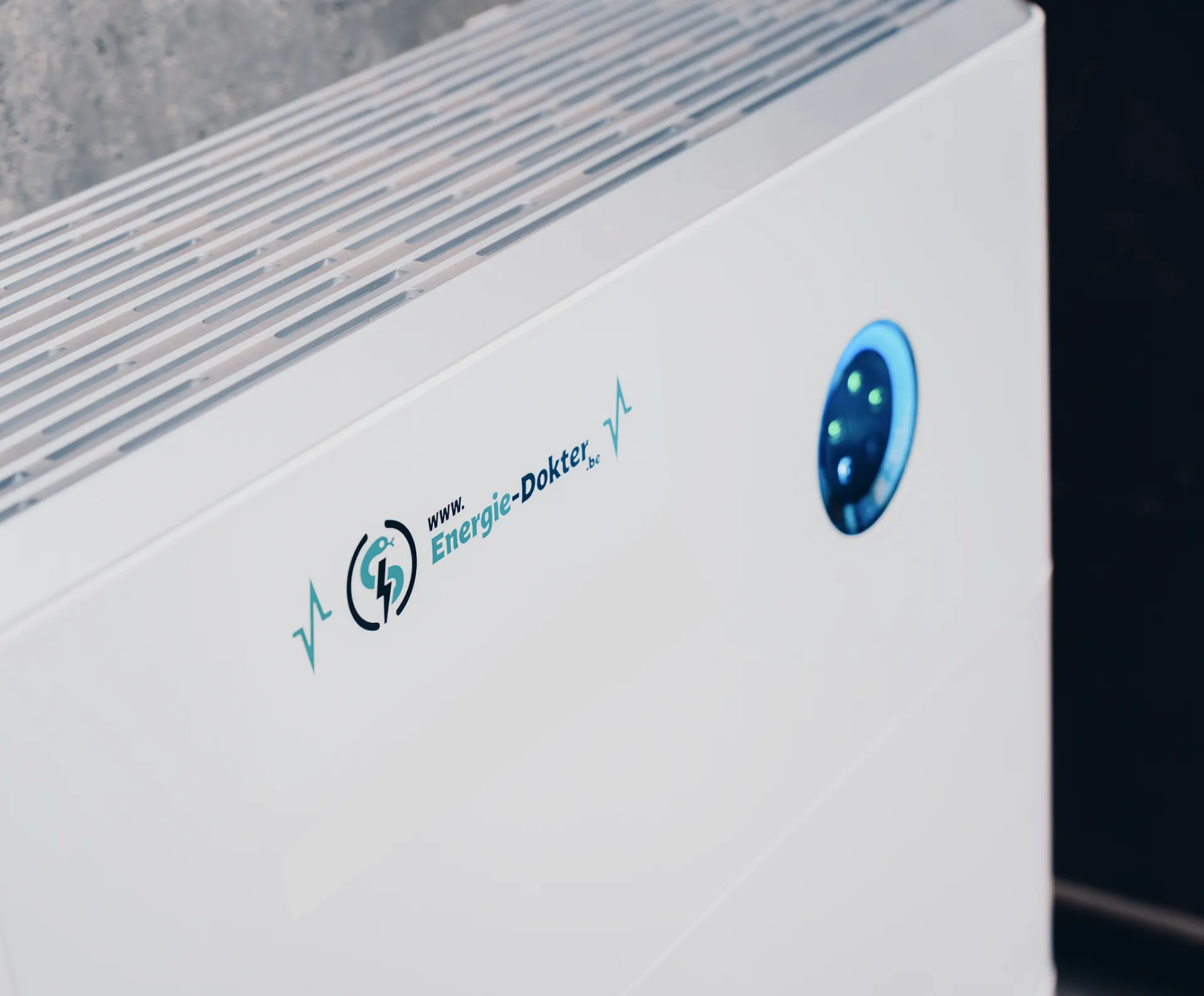 Close-up van een moderne witte thuisbatterij met het Energie-Dokter logo en een blauw verlicht bedieningspaneel.